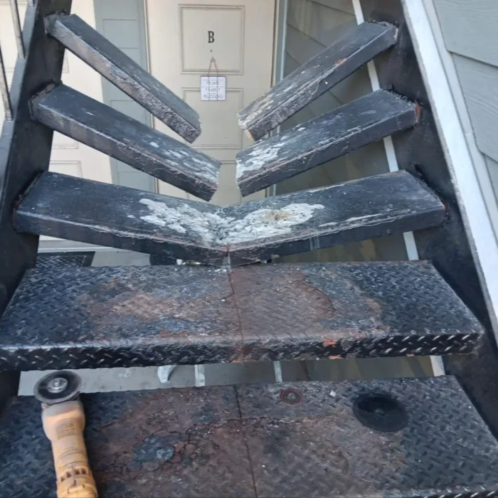 Broken and deteriorated metal stair treads before repair at a multi-family property in Indianapolis, Indiana.