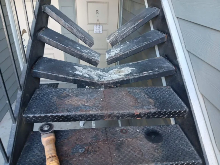 Broken and deteriorated metal stair treads before repair at a multi-family property in Indianapolis, Indiana.
