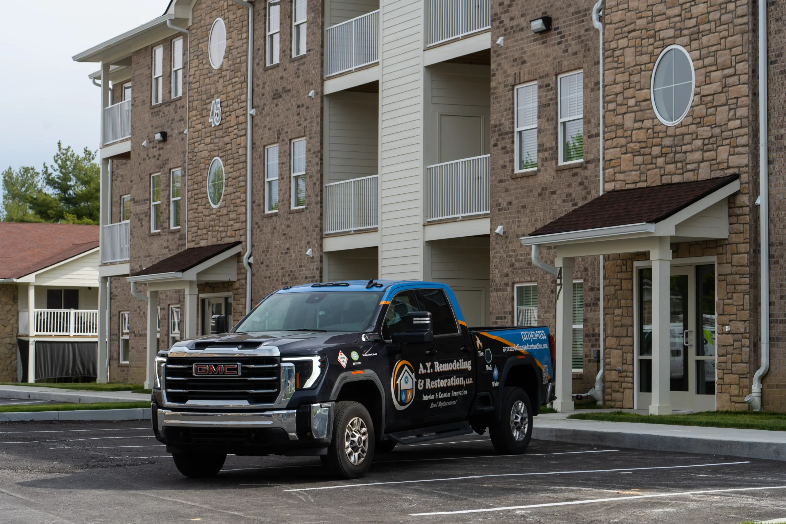 AY Remodeling & Restoration company truck parked at a multifamily construction project site in Greenwood, Indiana.