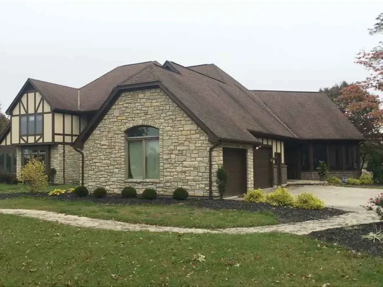 Before roof replacement on a stone exterior home showing original shingle roof condition