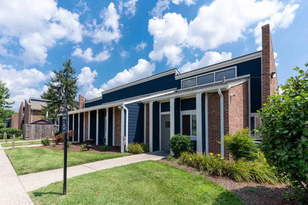 Freshly painted apartment leasing office exterior in Louisville, Kentucky featuring updated blue siding, brick accents, and white trim by AY Remodeling & Restoration.