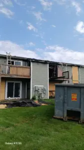 Fire and smoke damage to apartment building in Indianapolis, Indiana before restoration, showing burned exterior, roof damage, boarded windows, and debris removal.