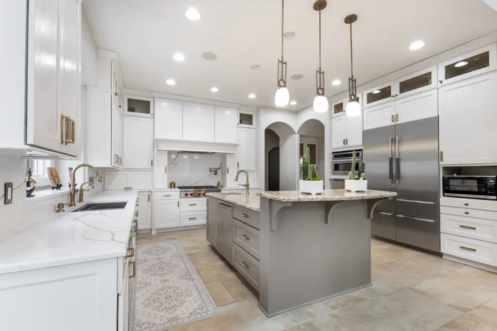Kitchen remodel with painted white cabinets, updated countertops, large island, and modern lighting in Carmel home