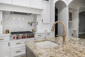 Close-up of renovated kitchen with updated countertops, gold faucet, white cabinetry, and contrasting island in Carmel, Indiana