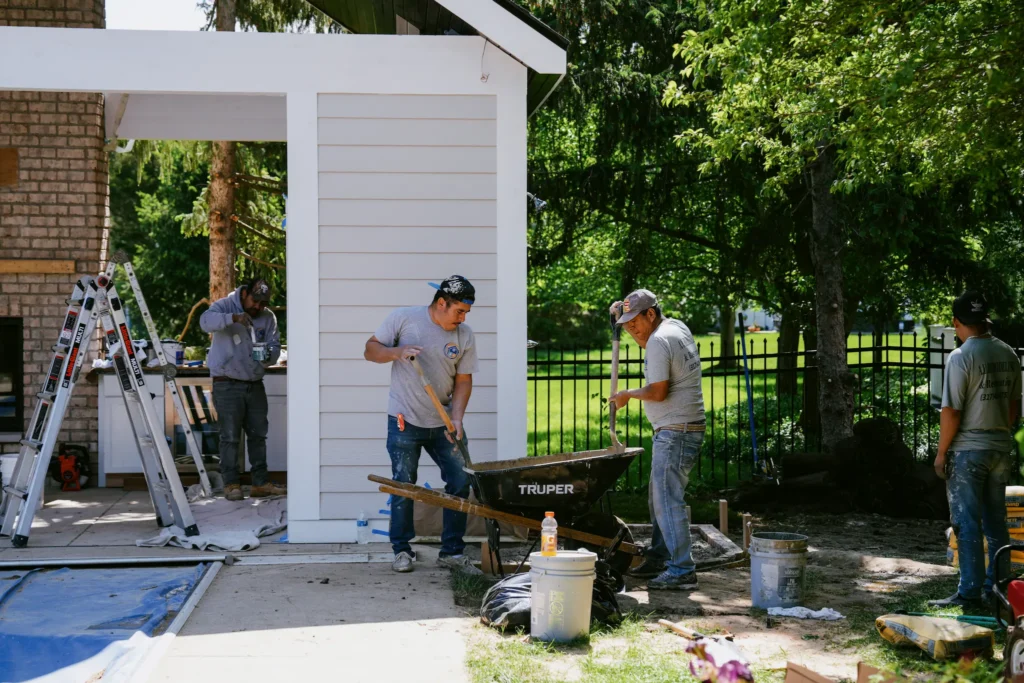 Construction crew working on pool house addition and concrete installation at residential property