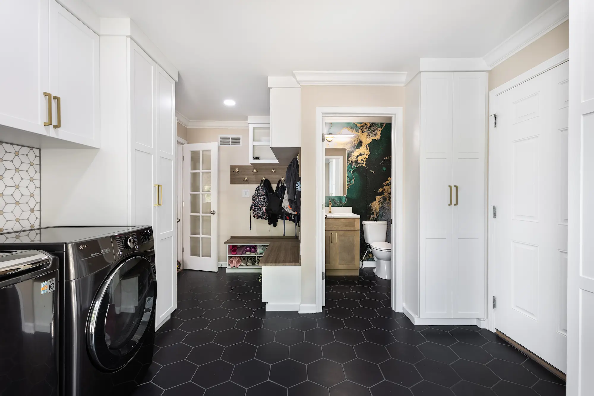 Laundry room remodel featuring custom cabinetry, mudroom bench, and updated powder room entrance in Carmel, Indiana