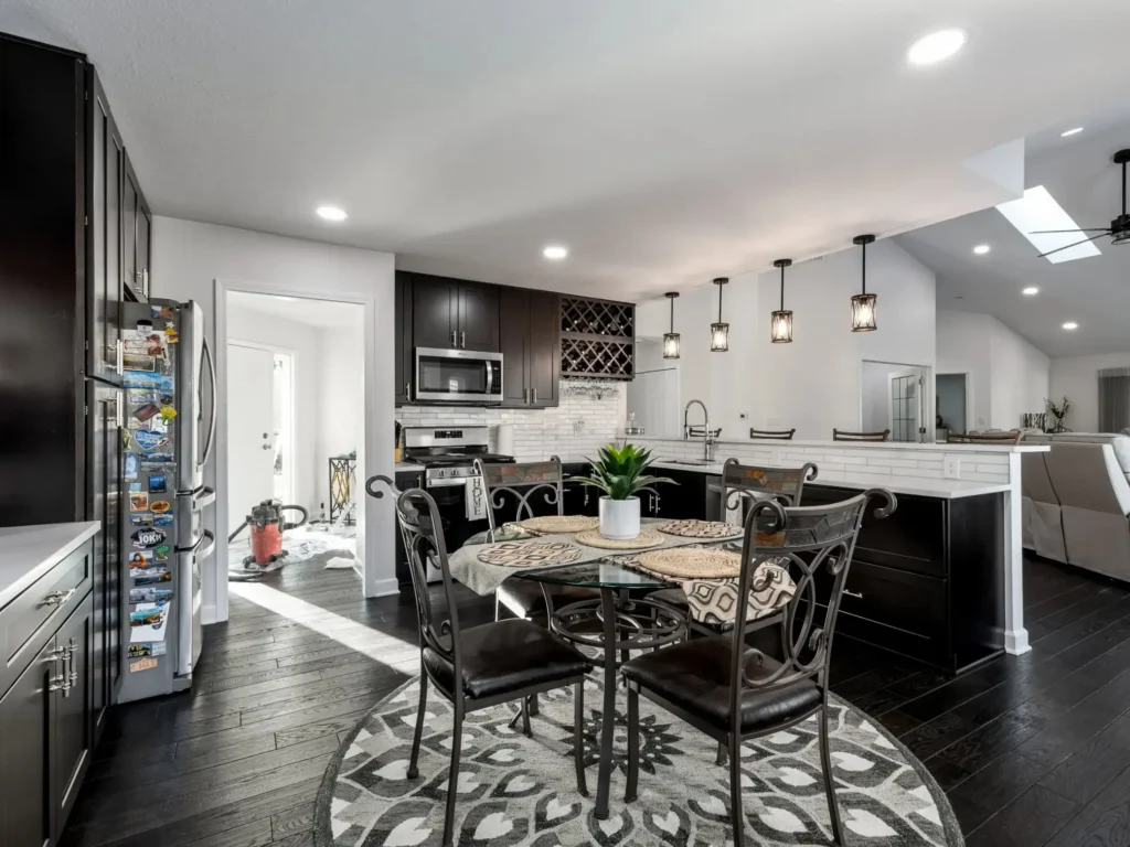 Open concept kitchen and dining area remodel with dark cabinets, quartz countertops, and updated lighting in Indianapolis home