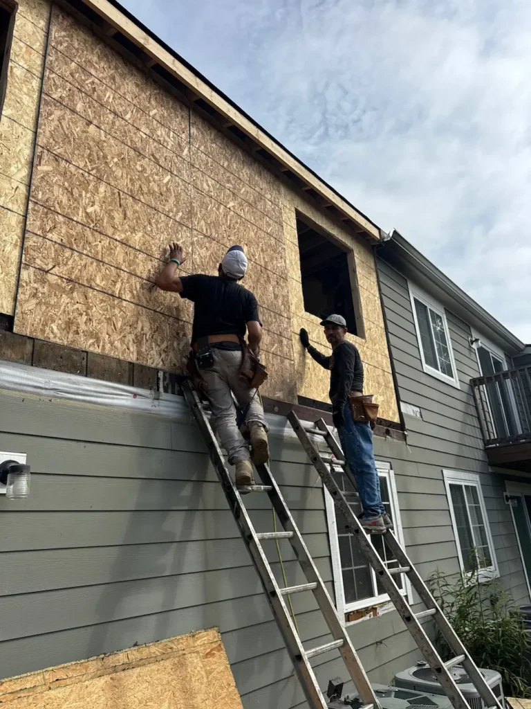 Contractors installing exterior wall sheathing during fire damage reconstruction in Indiana