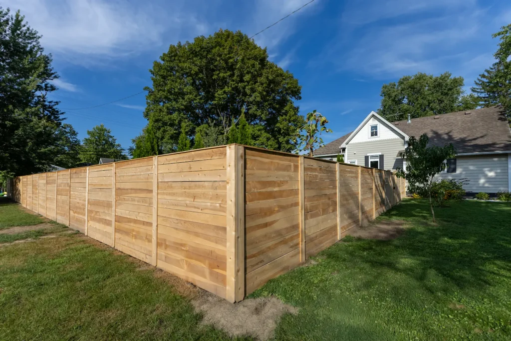 New horizontal wood privacy fence wrapping around the corner of a backyard