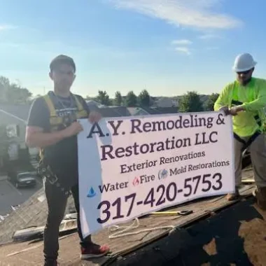 AY Remodeling & Restoration team holding company banner on a roofing project in Indiana